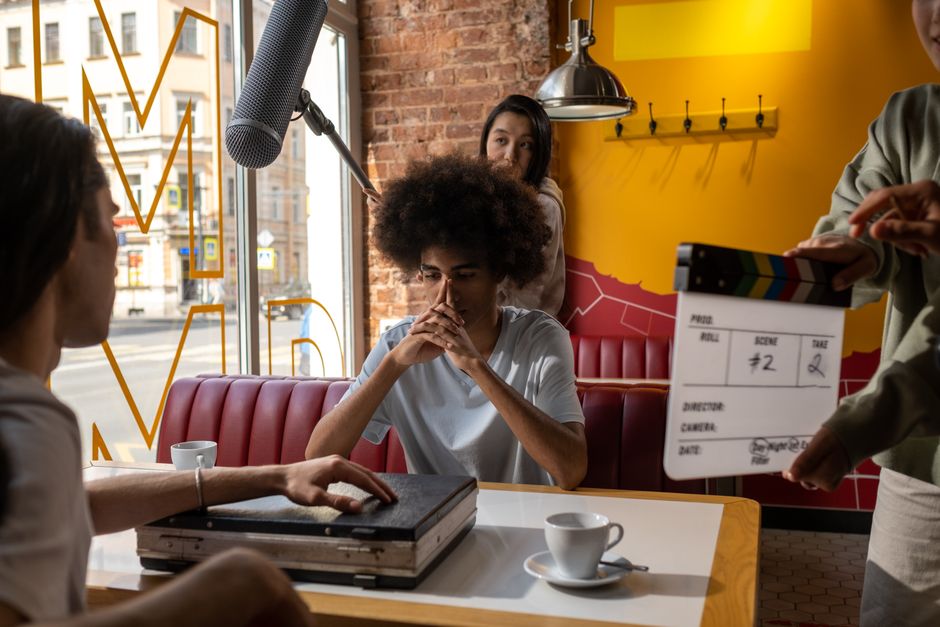 Diverse film crew capturing a scene indoors with clapperboard and boom mic.