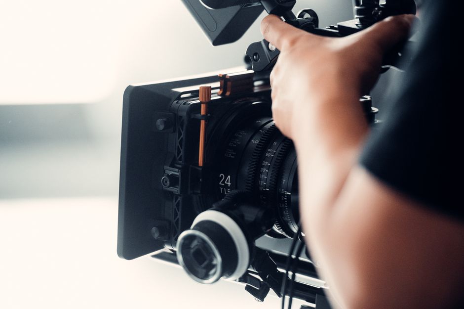 A professional video camera being operated by a person during filming indoors.