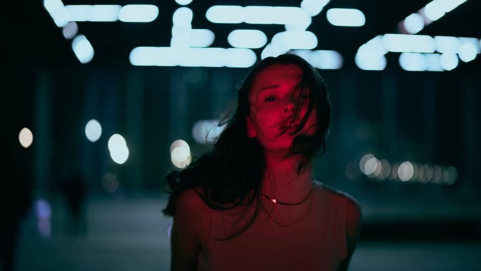 A creative portrait of a woman illuminated by neon lights with a dramatic red glow.