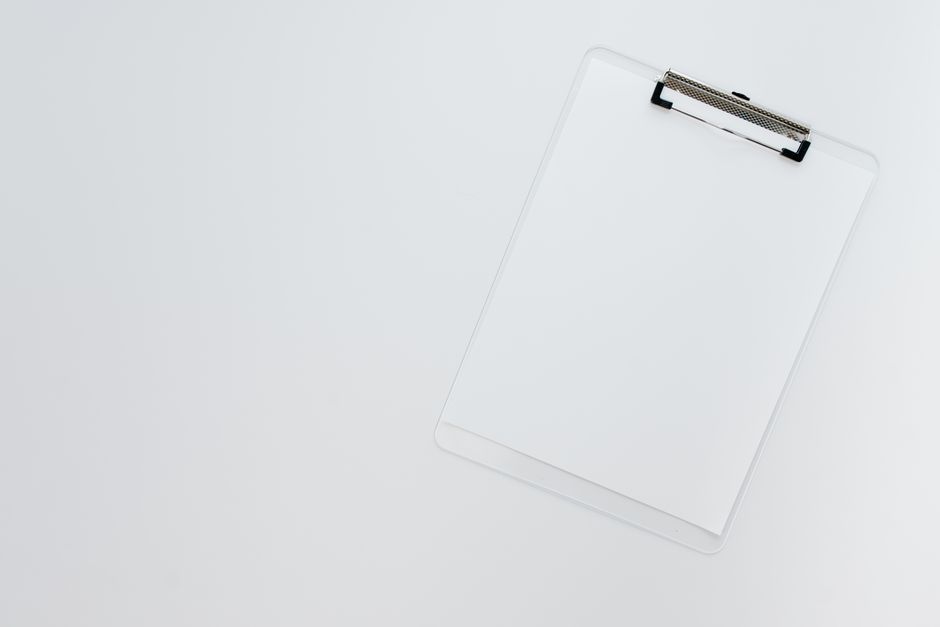 Minimalist top view of a transparent clipboard on a white background offering ample copy space.