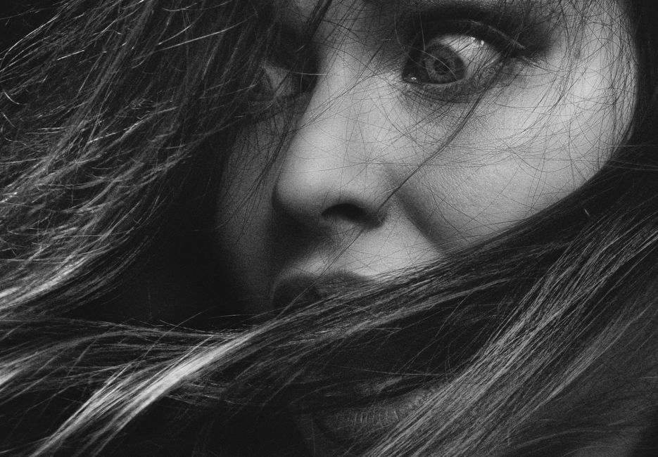 Intense monochrome close-up of a woman's expressive face and hair.