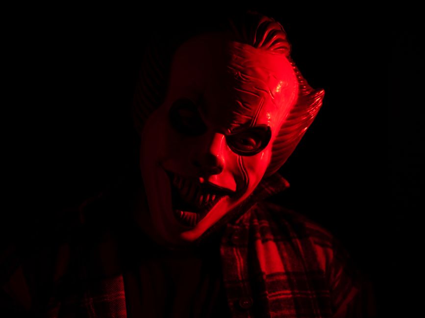 A terrifying masked figure illuminated by red light, perfect for Halloween-themed designs.