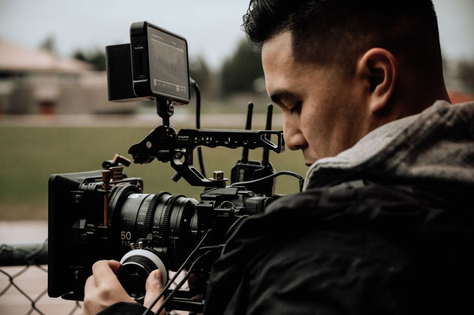 A cameraman using professional equipment for filming outdoors, focused on capturing high-quality footage.