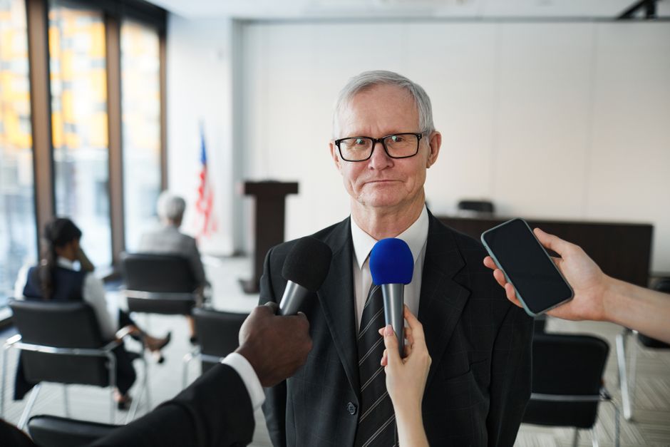 Senior man in formal attire being interviewed in a conference room.