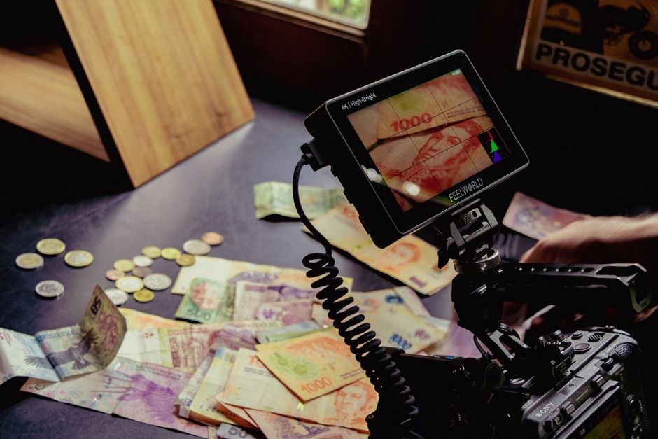 Camera setup capturing various global currencies on a table, detailed professional shot.