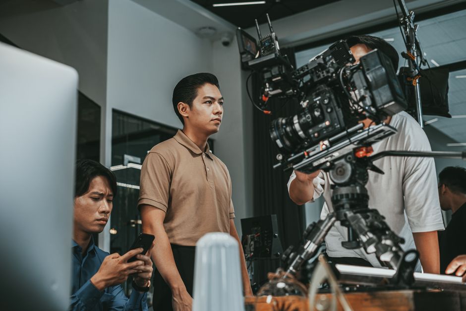 Film crew working with advanced camera equipment indoors, focusing on a project.