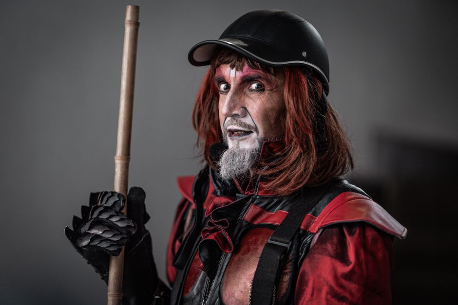 A dramatic street performer in a striking red and black costume with makeup.
