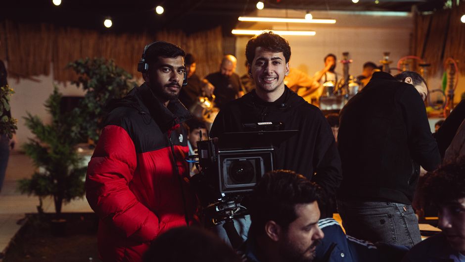 Camera crew capturing a scene indoors with professional equipment in cozy atmosphere.
