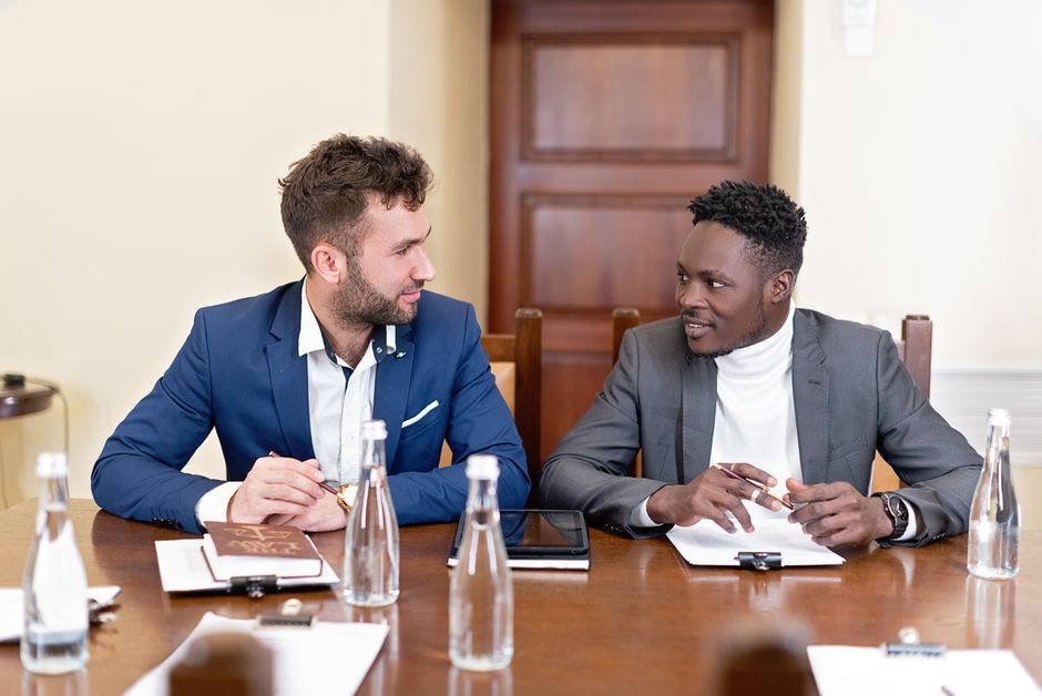 Two businessmen discussing work, seated at a conference table.