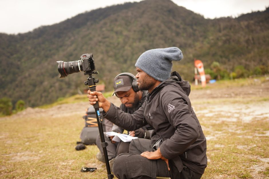 Two filmmakers preparing for a shoot in a picturesque mountain setting.