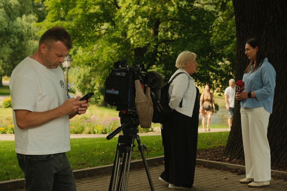 News crew conducting outdoor interview with professional camera setup in a lush park.