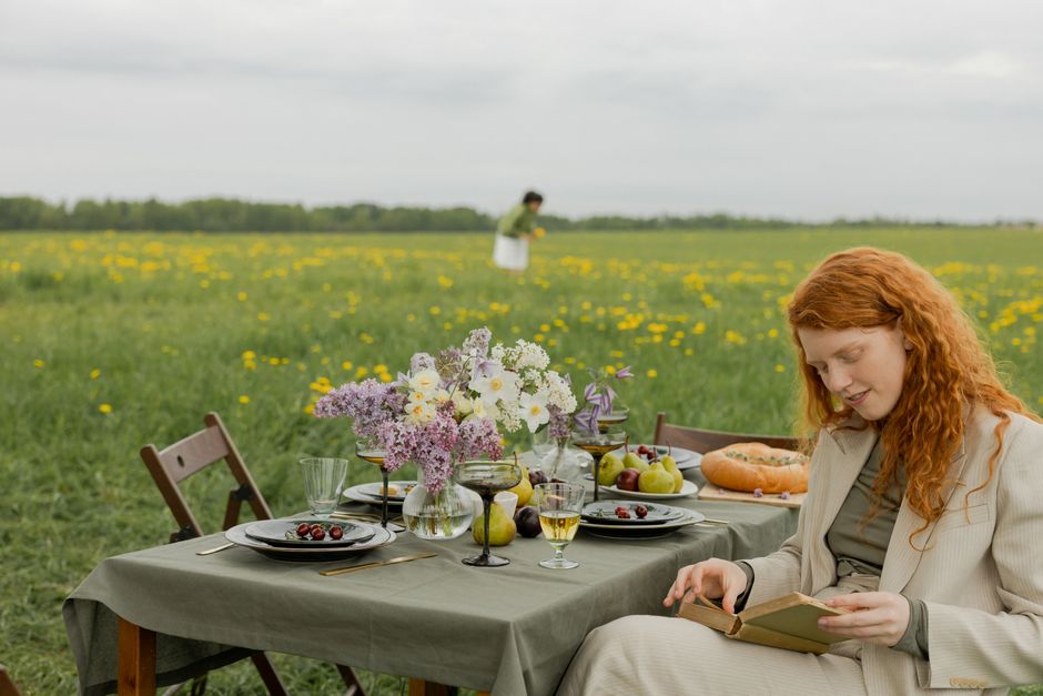 A peaceful outdoor picnic with flowers, food, and reading in a blooming field.