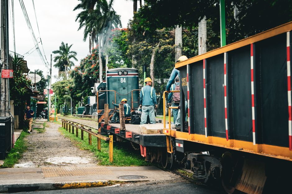 Workers on train tracks surrounded by lush greenery in San José, Costa Rica.