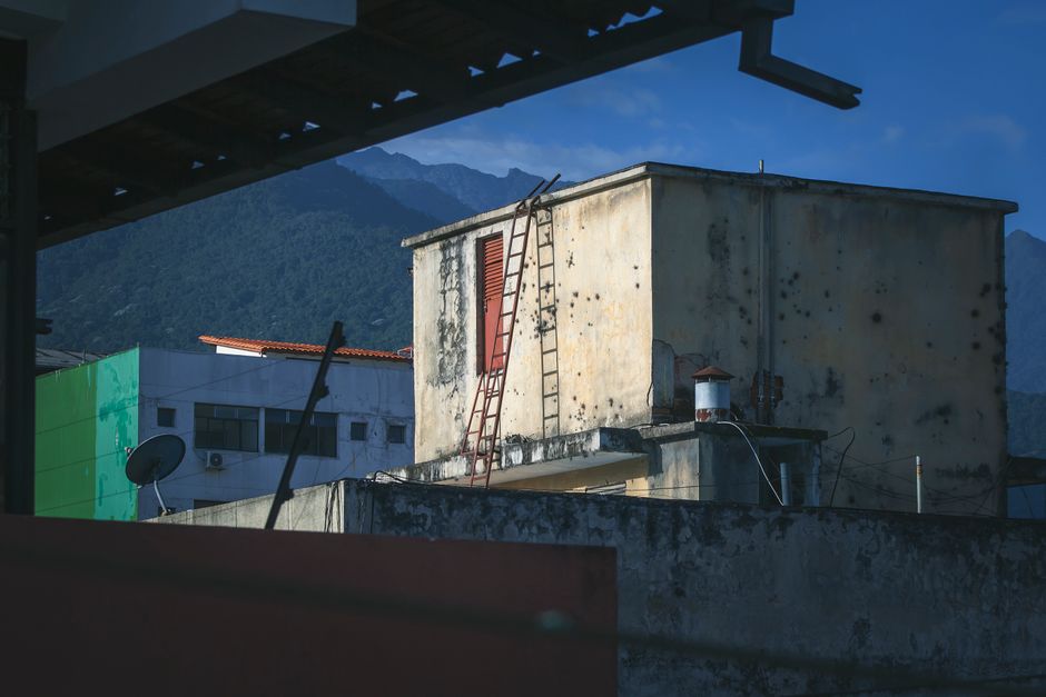 A decaying rooftop with colorful walls against a mountainous backdrop in Venezuela.