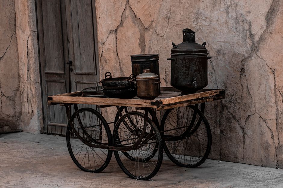 Old wooden cart with metal pots in an urban street of Dubai, showcasing a vintage vibe.