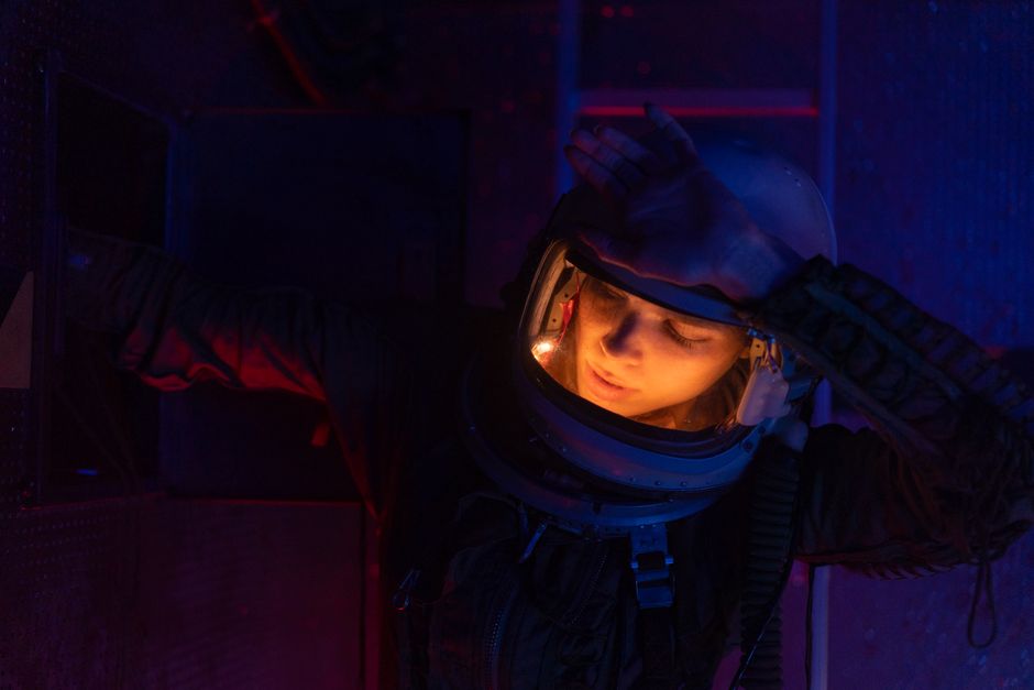 Close-up of a female astronaut in a dimly lit spaceship, exploring with focus.
