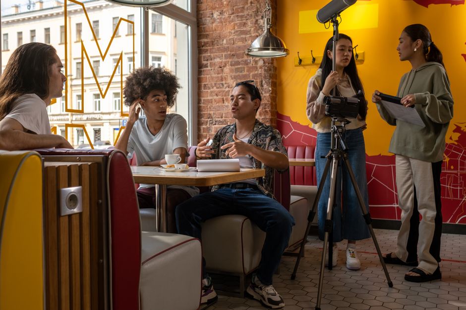 Group of friends filming a project in a vibrant cafe setting.