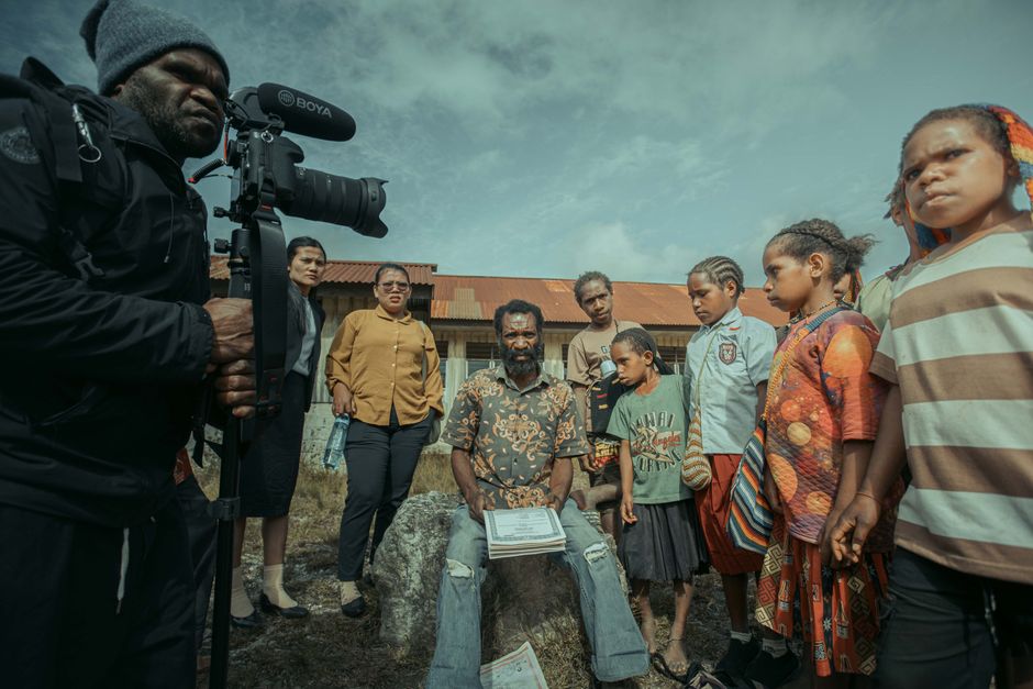 A filmmaker capturing a diverse group of people outdoors, emphasizing community and storytelling.