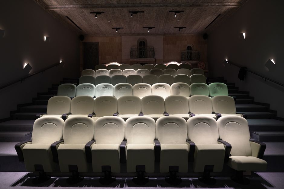 An empty theater with neatly arranged plush seating and subtle lighting, creating an intimate ambiance.