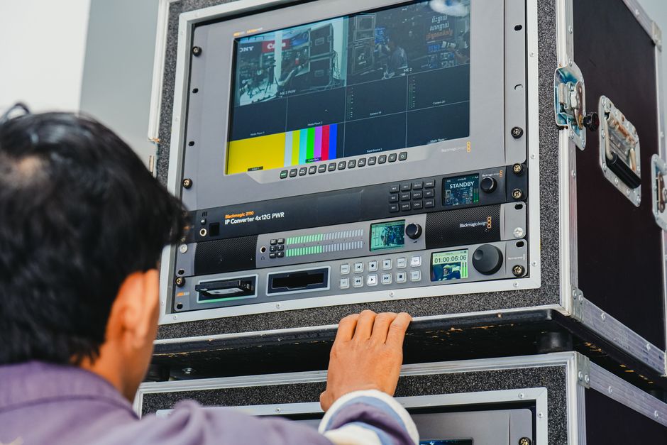 A technician manages professional broadcasting equipment in a control room setting.