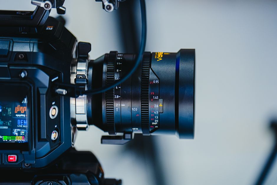 Detailed view of a professional video camera lens with focus and zoom settings showing.