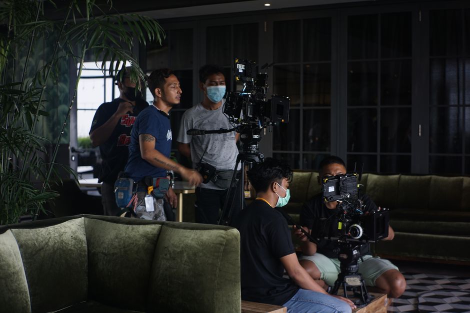 Film crew setting up camera equipment for indoor scene. Teamwork and filmmaking in action.