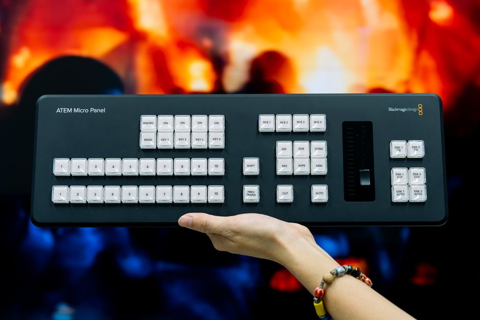 ATEM Micro Panel held against a vivid background, highlighting its professional video control features.
