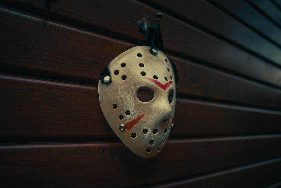 Vintage hockey mask reminiscent of horror movies hanging on a cabin wall, evoking suspense and mystery.