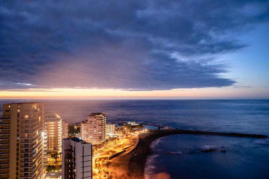 Aerial view of Puerto de la Cruz at sunset, highlighting city lights and coastal beauty.