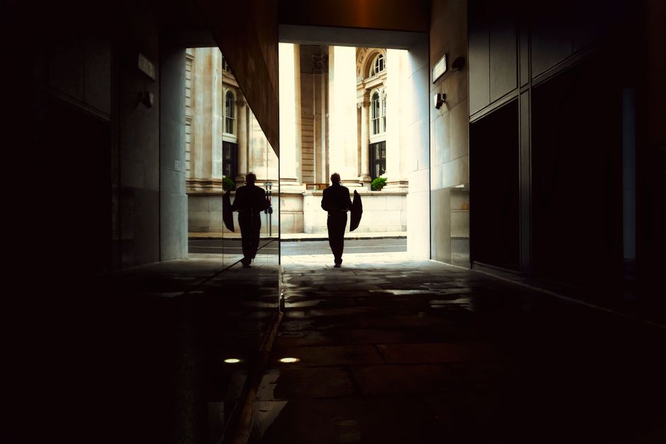 A lone figure walks through a moody alleyway in England, with reflections and dramatic lighting creating a cinematic atmosphere.