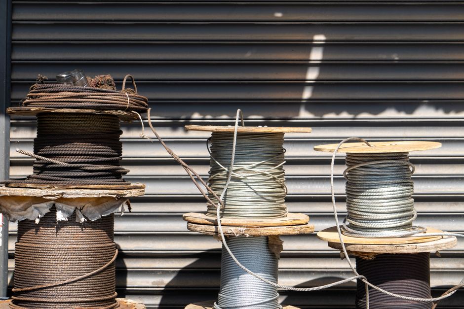 Multiple large spools of industrial cable placed outdoors in front of a closed shutter.
