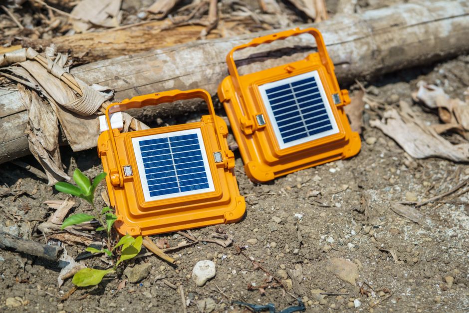 Two orange portable solar panels on dry ground, highlighting renewable energy in arid conditions.