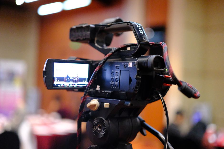Close-up of a camcorder recording a business conference indoors.