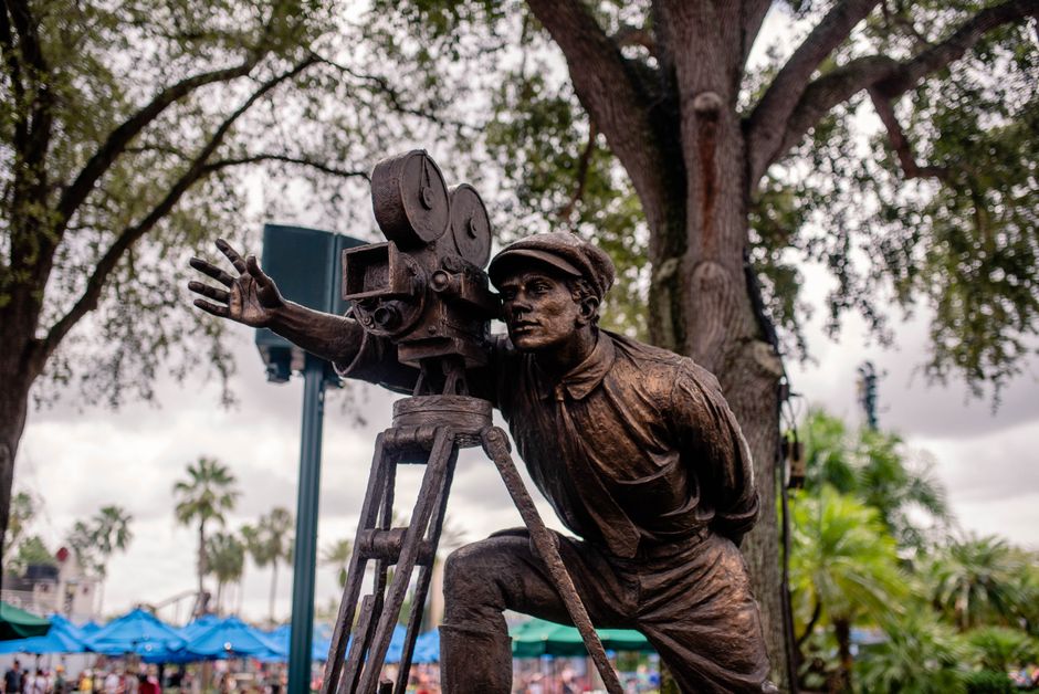 Statue of a filmmaker with vintage camera, located outdoors at a park in Orlando, Florida.