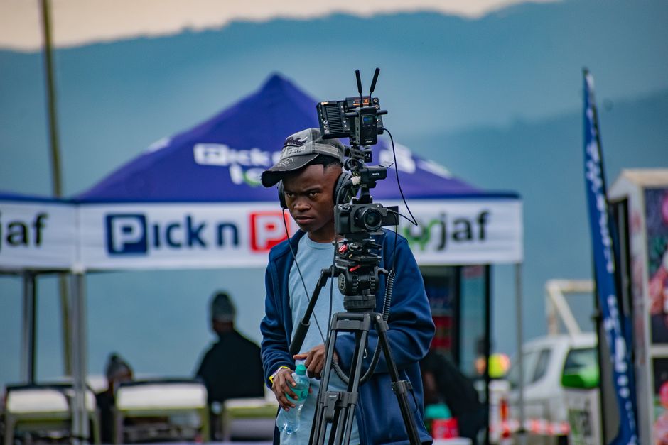Filmmaker operating camera equipment at an outdoor event in Malkerns, Eswatini.