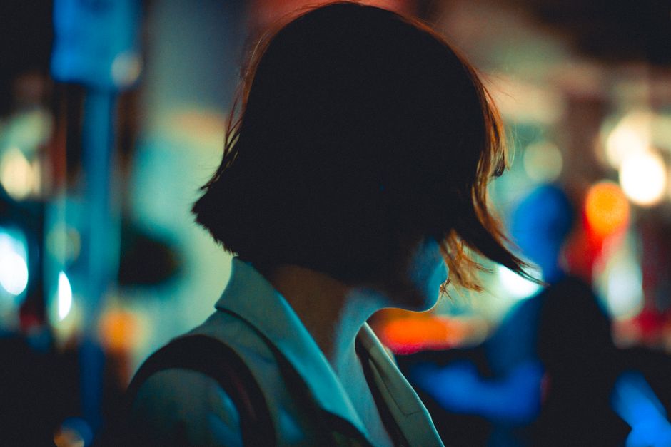 Artistic portrait of a woman at night in Hong Kong's vibrant city streets.
