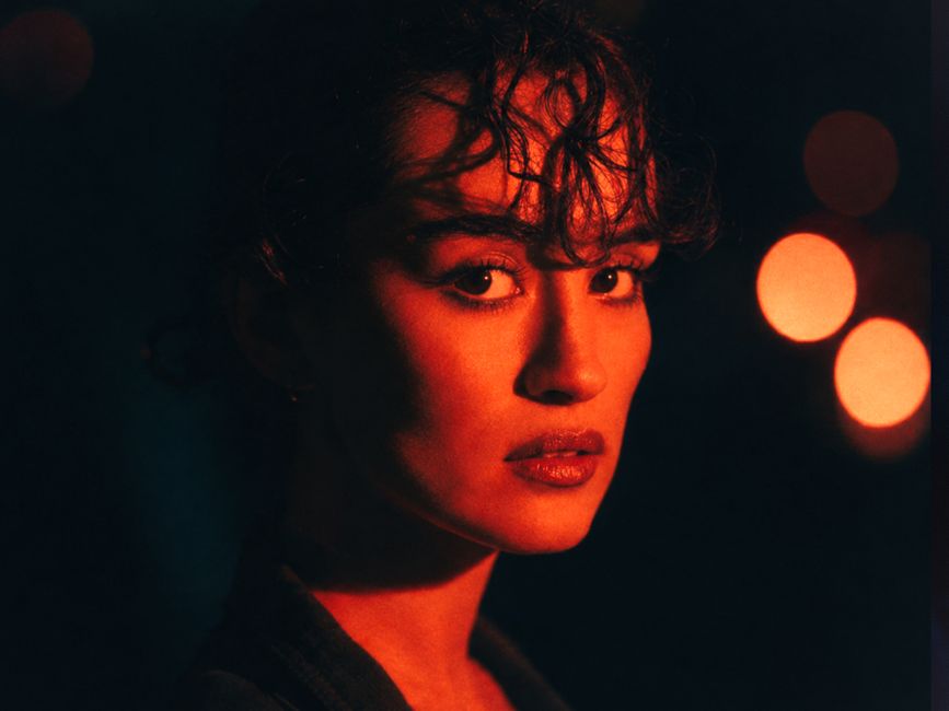 A dramatic portrait of a woman with bold lighting and bokeh effect.