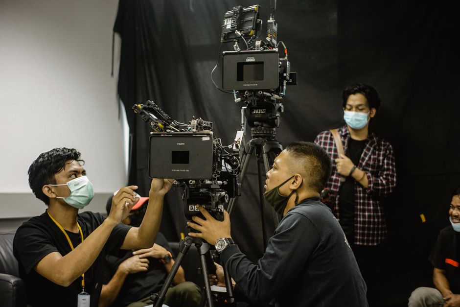 Team of videographers setting up professional camera equipment in a studio environment.