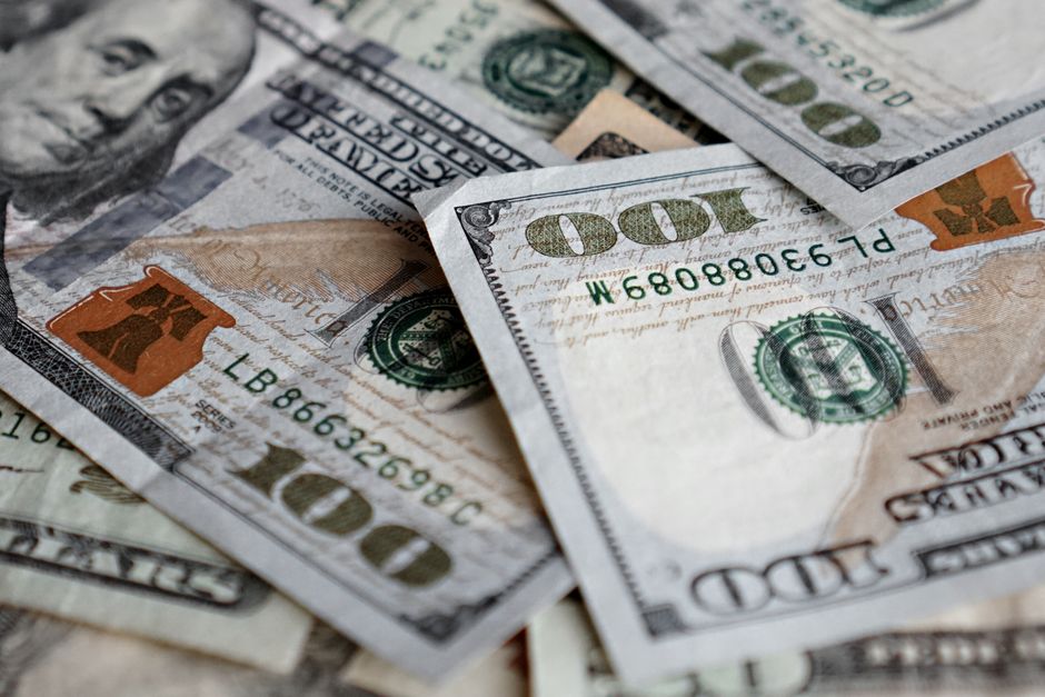 Stack of US dollar bills showing one hundred dollar notes prominently.