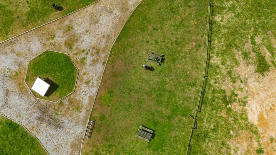 Scenic aerial view of a park featuring picnic tables, pathways, and a grassy lawn area.