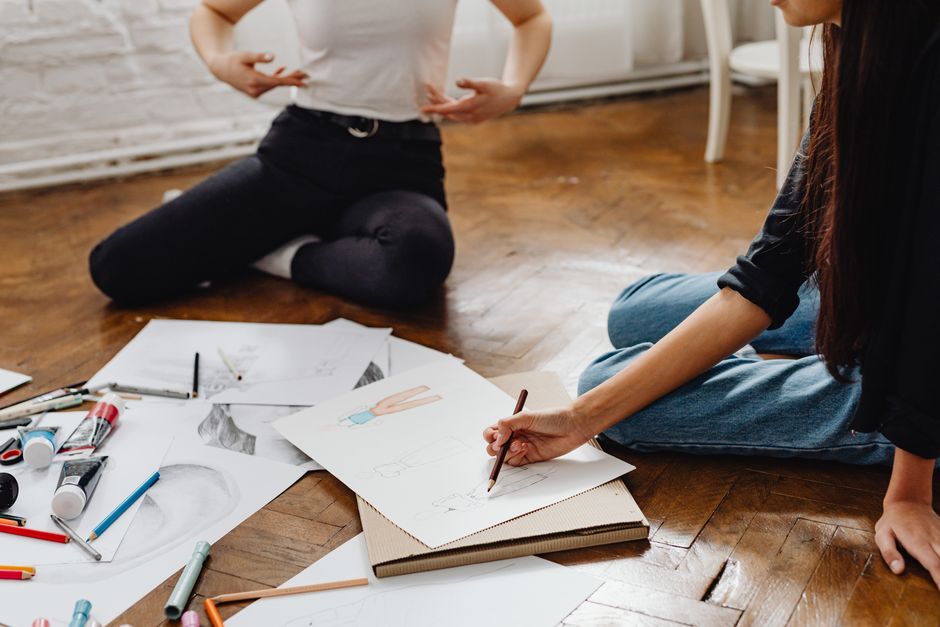 Fashion designers collaborating on sketches and drawings in a studio setting.