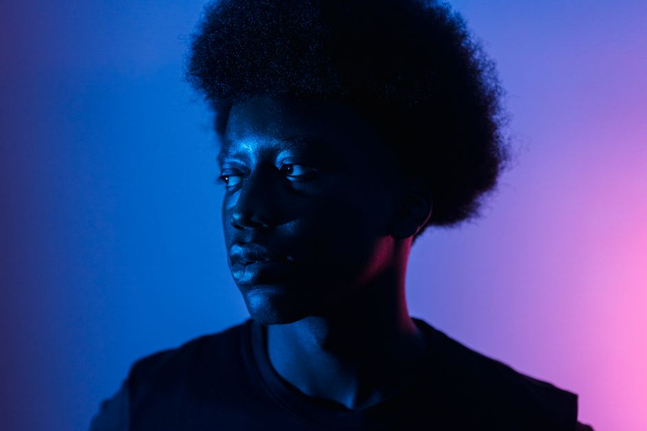 A stylish portrait of a man with afro hair in monochrome lighting, creating a dramatic effect.