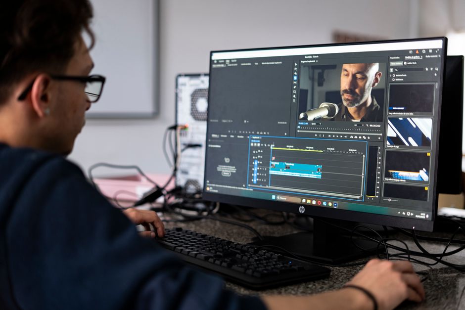 A video editor working on a project using a desktop computer in a modern office setting.