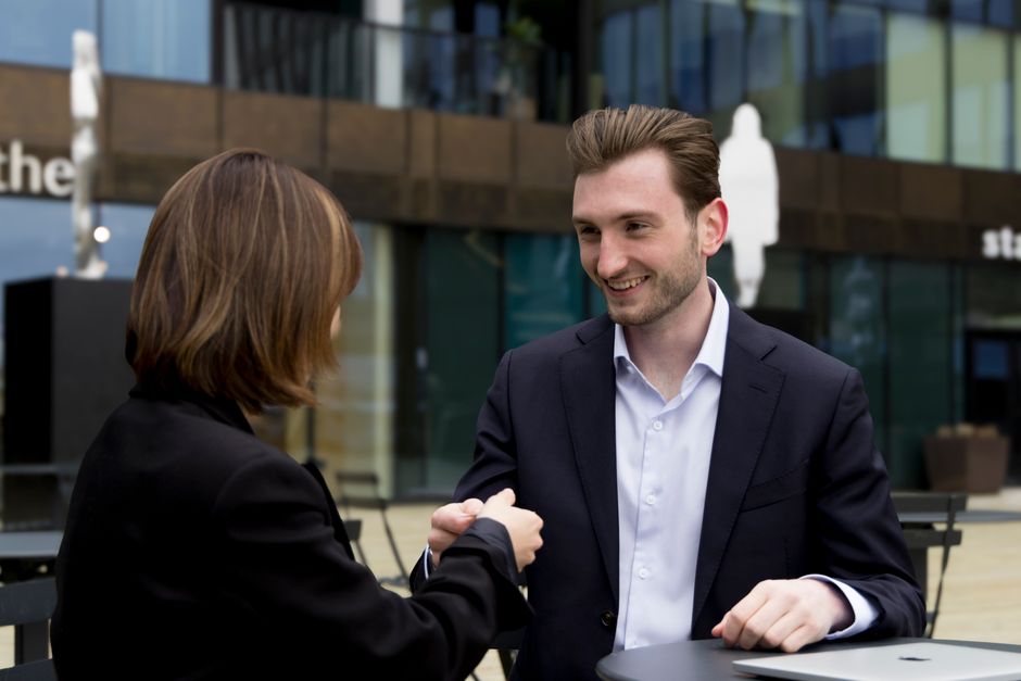 Professional outdoor business meeting featuring a handshake between colleagues