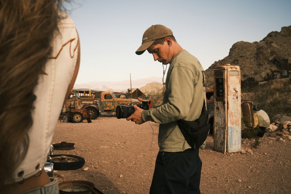 Photographer capturing vintage desert scene in Spring Valley, Nevada, with classic cars and gas pump.