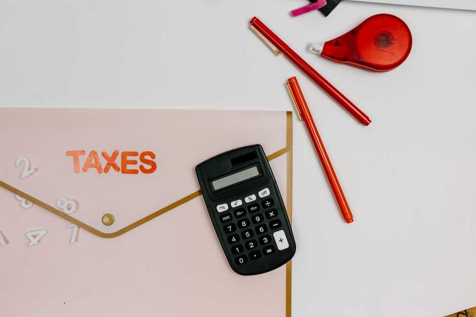 Flat lay image featuring a calculator, pens, and a folder labeled 'TAXES', perfect for finance-related themes.