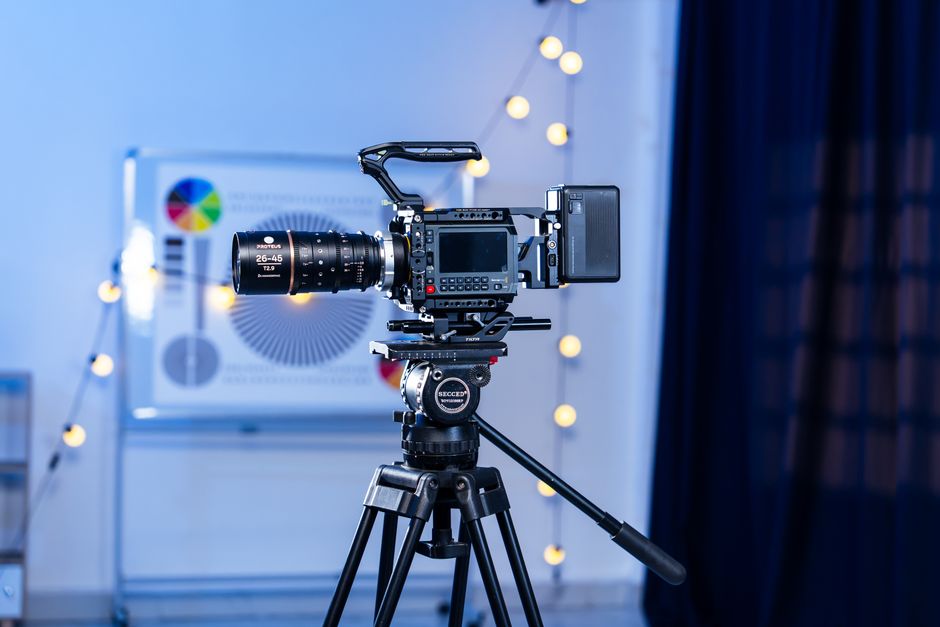 A high-end video camera mounted on a tripod in a dimly lit studio with elegant lighting.