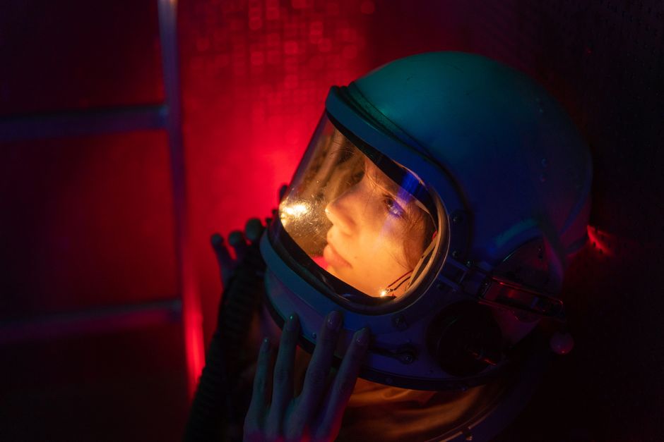 A spacewoman in a helmet immersed in red and blue lighting, evoking a sense of exploration.