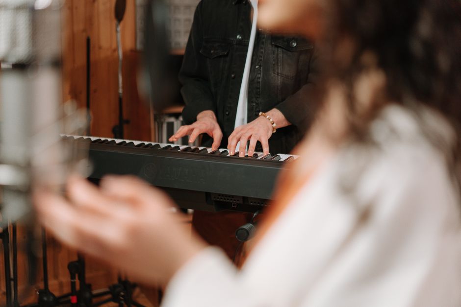 Close-up of hands playing a keyboard in a cozy recording studio setting.