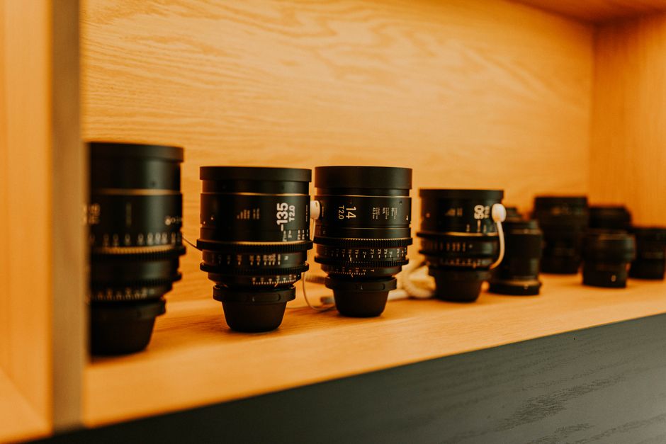 A variety of camera lenses displayed on a wooden shelf, perfect for photography enthusiasts.